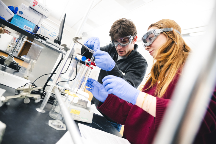 two students conduct chemistry experiment in lab
